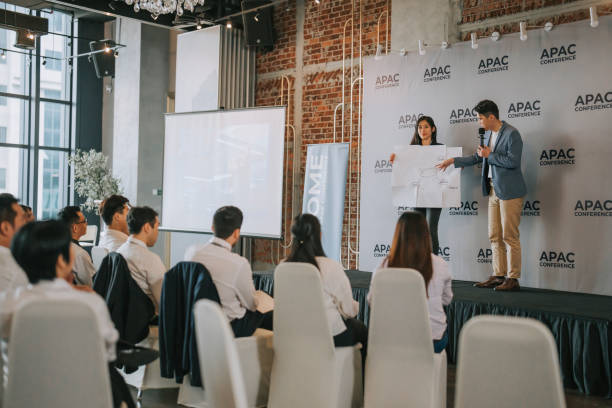 istock Team building asian group presenting ideas in front of all workshop participants in APAC business conference discussion 1529815573