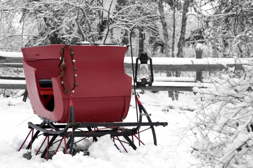 A vintage snow sleigh with an oil lantern parked in the snow