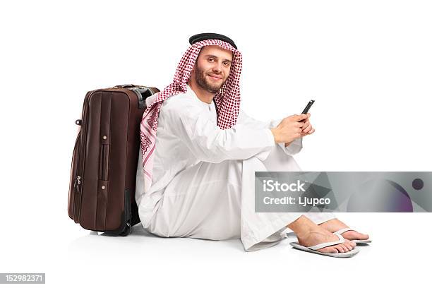 Арабские Человек Сидит И Набрав Sms На Его Cellphone — стоковые фотографии и другие картинки Багаж