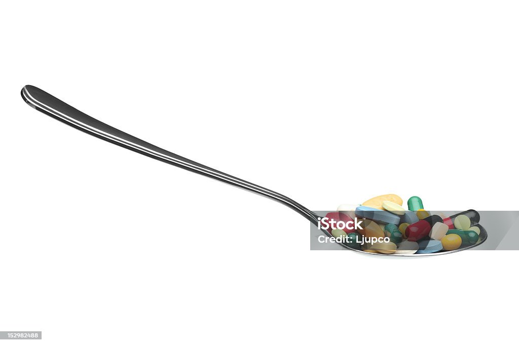 Muchos de los comprimidos y de las cápsulas en una cuchara - Foto de stock de Acero libre de derechos