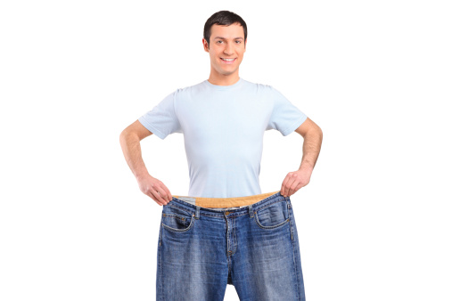 Portrait of a weight loss male showing his old jeans isolated on white