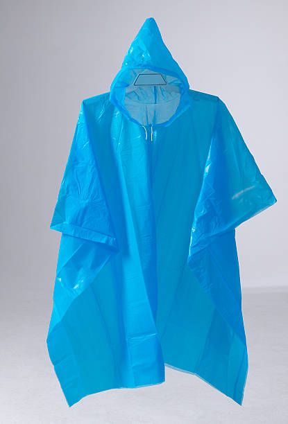 Blue rain poncho hanging Blue rain poncho hanging on grey background raincoat stock pictures, royalty-free photos & images