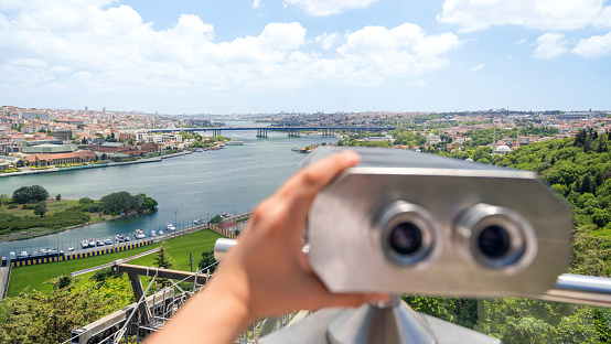 A man holding binoculars on a viewpoint located in Balat district in Istanbul, Turkey. Golden Horn waterway and downtown on the background