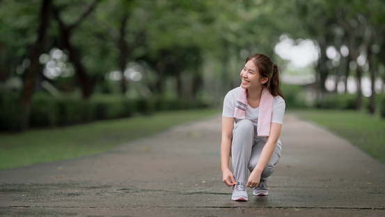 Young beautiful Asian woman jogging in the park happily, with a smile. Young Asian woman jogging for health care, exercise in the park, youth health care. concept health care life insurance