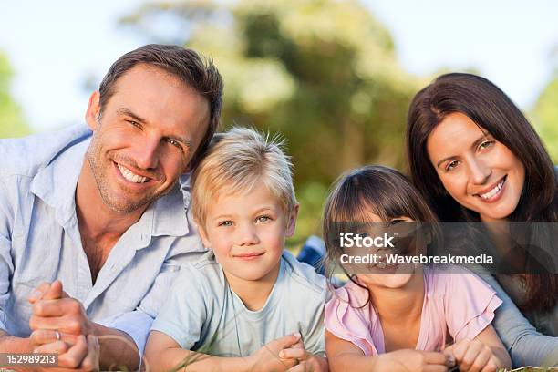 Foto de Família Deitado Para Baixo No Parque e mais fotos de stock de Abraçar - Abraçar, Adulto, Amor