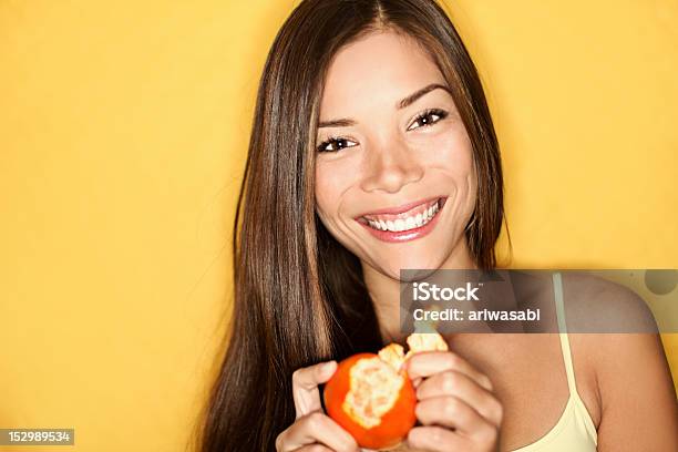 Smiling Woman Peeling Orange Over A Yellow Backdrop Stock Photo - Download Image Now