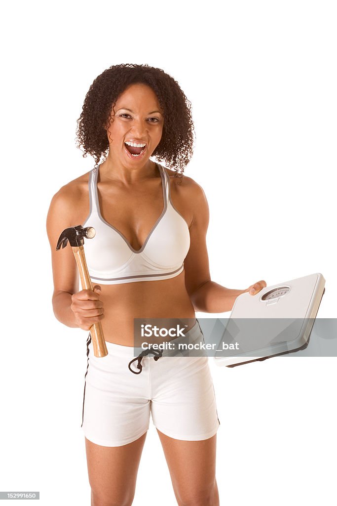 Woman fighting for weight loss Ethnic woman in sporty outfit hits weight scales by hammer 30-39 Years Stock Photo