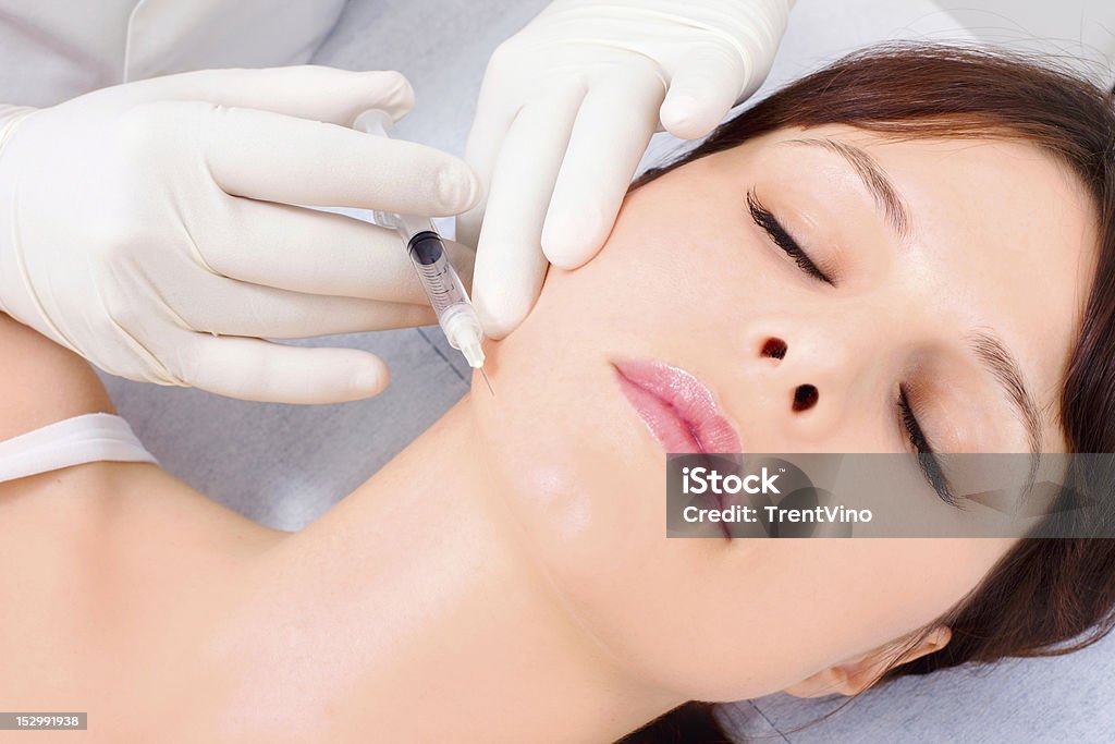 woman receiving an injection of botox from a doctor young caucasian woman receiving an injection of botox from a doctor  isolated on white background 30-39 Years Stock Photo