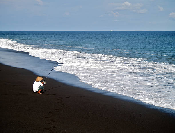 Fisherman on a black sand beach stock photo