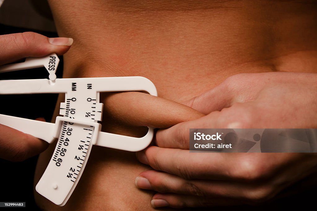 Pinching abdomen fat A young women, measuring her body fat on her abdomen. The Human Body Stock Photo