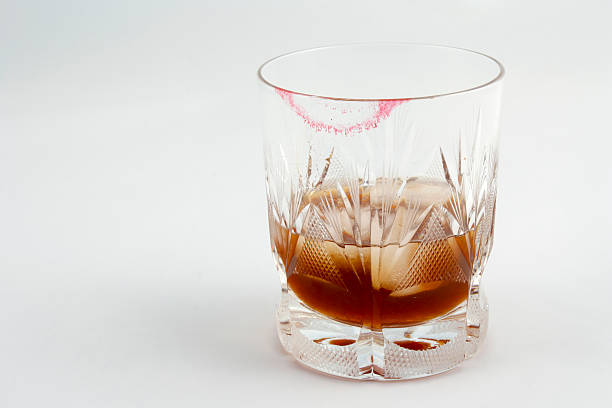 Red lipstick marks on whiskey glass.