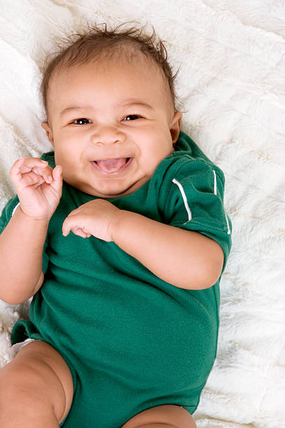 ethnic multiethnic Baby boy in green outfit Young ethnic multiracial little boy on bed human tongue stock pictures, royalty-free photos & images