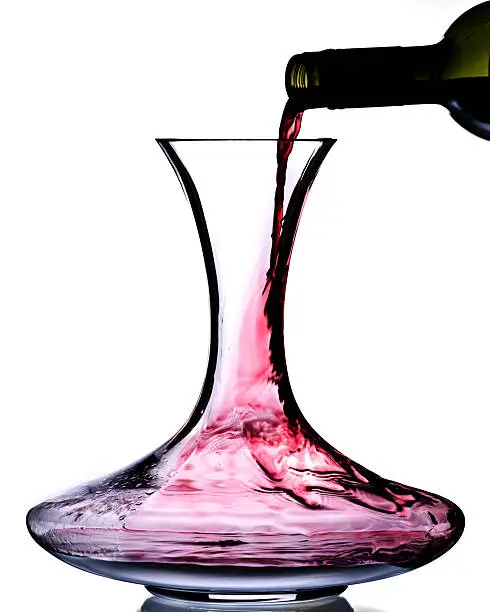 red wine being poured into glass decanter