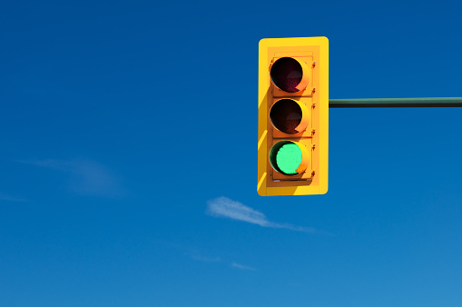 Traffic lights set on green against clear blue sky
