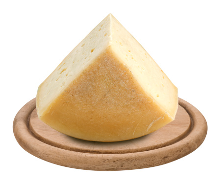 piece of italian cheese Montasio on a wooden plate