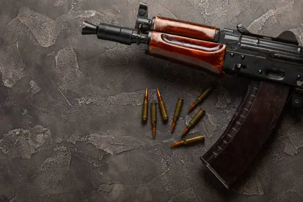 Photo of Bullets and ammo magazine with kolashnikov assault rifle on black texture marble.Composition with place for text.Rifle and carbine cartridges on wooden background.Military concept.Copy space