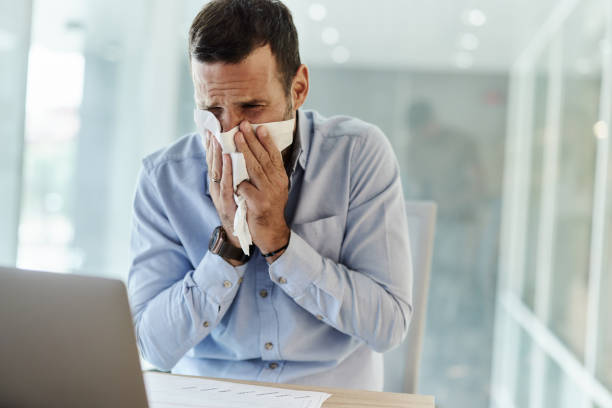 istock Sick businessman blowing his nose in the office. 1529992590