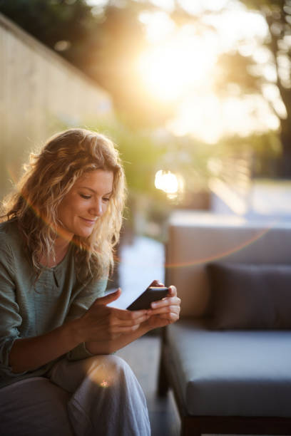 istock Smiling woman text messaging on cell phone on a patio. 1530007990