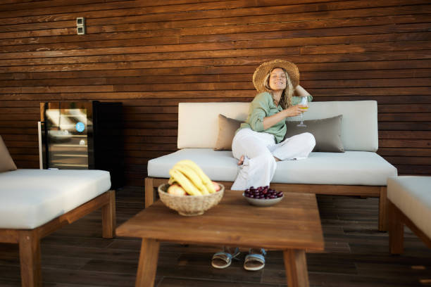 istock Happy woman with a hat relaxing on sofa at patio. 1530012224