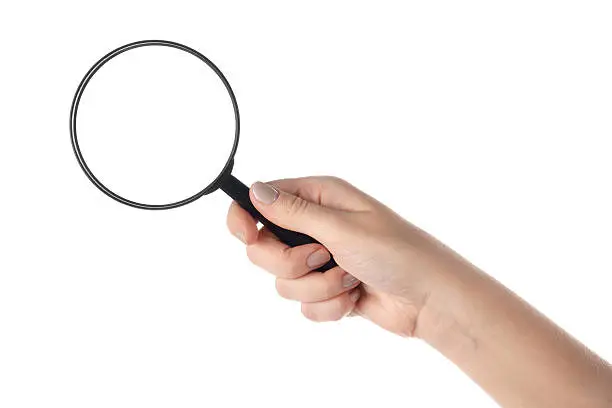 Female hand holding the magnifying glass isolated on white background