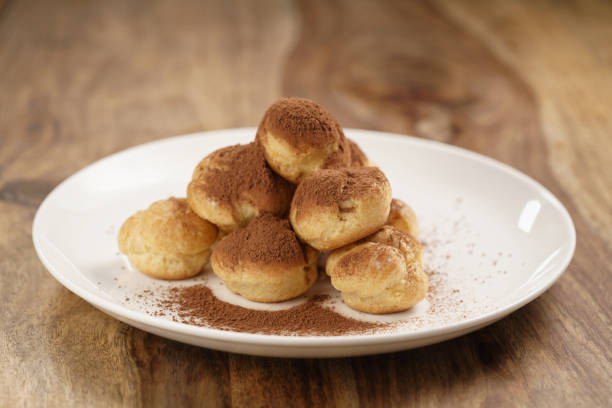 istock profiteroles covered with cocoa powder on white plate on wooden table 1530018522