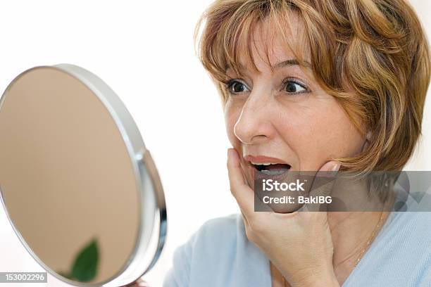 Mature Woman Holding Face And Looking Into Mirror Surprised Stock Photo - Download Image Now