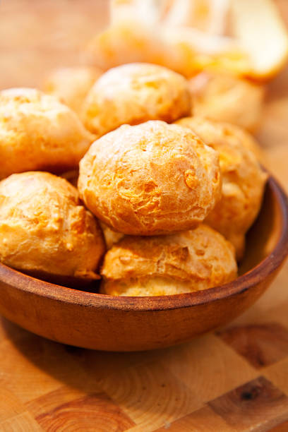 A wooden bowl filled with multiple cheese gougeres stock photo