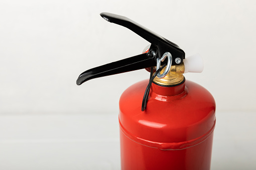 Fire extinguisher on a white wall. Red fire extinguisher indoors on the wall. Fire protection, home fire extinguisher. Mockup, space for text, copy space.