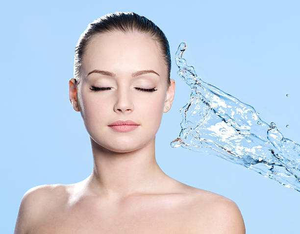 Clean skin on the face of young beautiful young woman and stream of water - blue background