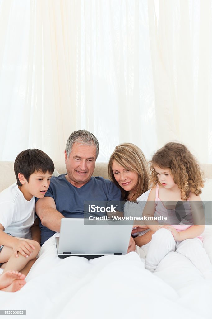 Crianças olhando opções de laptop com os avós - Foto de stock de Adulto royalty-free
