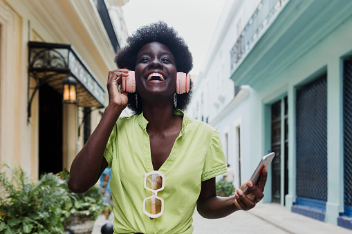 afro american woman with headphones dancing on the street, young caribbean girl in Latin America