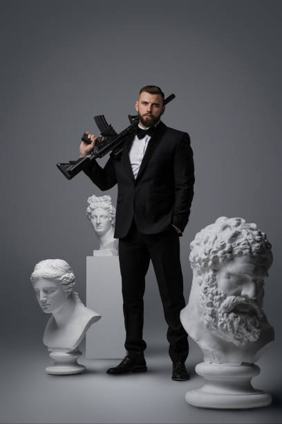 Stylish handsome man with beard wears a luxurious black suit and bowtie stock photo
