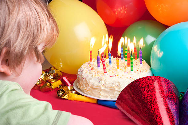 child blowing candles out stock photo