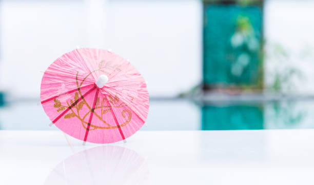 różowy papierowy parasol na brzegu basenu z miejscem na rozmytym tle - drink umbrella umbrella pink paper zdjęcia i obrazy z banku zdjęć