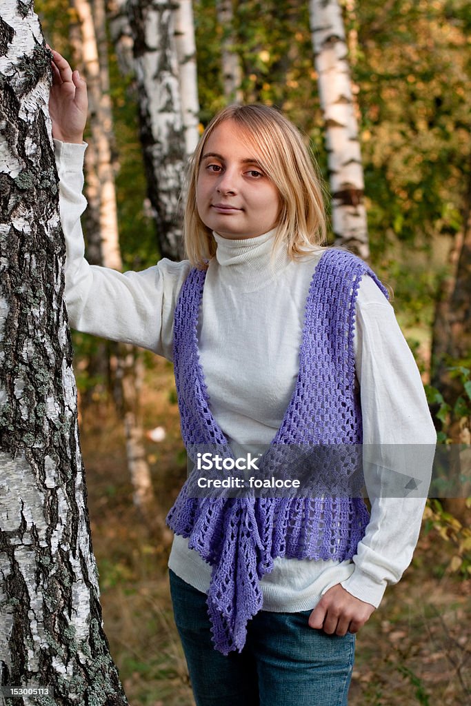 Standing girl A girl in a lilac vest and white polo-neck sweater and jeans in a forest. Adult Stock Photo