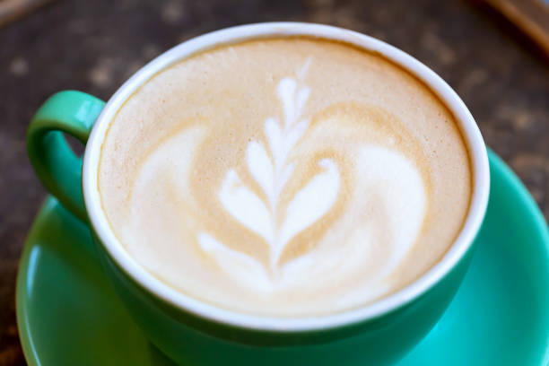 istock Aromatic coffee with foam and pattern in green cup close-up 1530051295