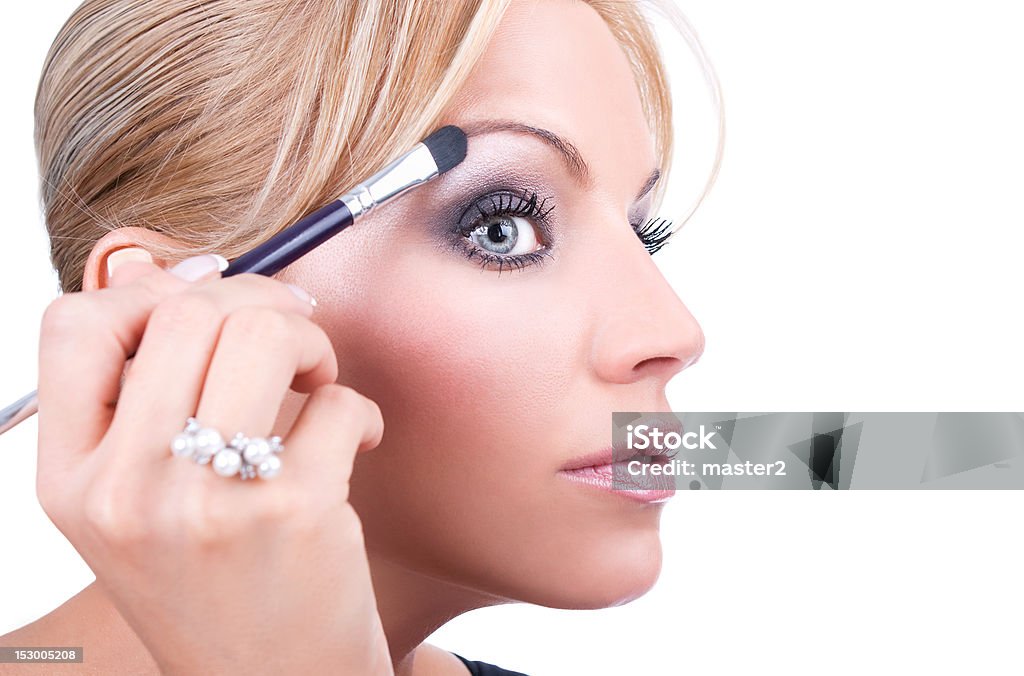 Nice caucasian model applying makeup with brush Nice caucasian model applying makeup with brush, isolated on white background Adult Stock Photo