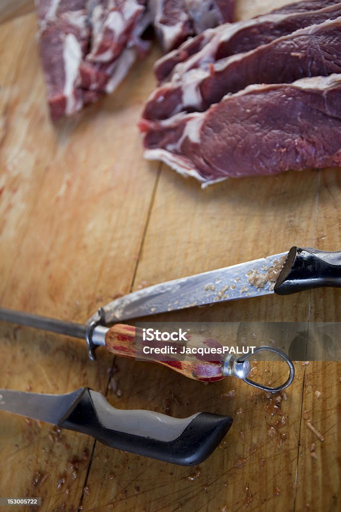 Inside A Butcher Wooden block of a butcher, with beef, sharpener and knives Business Stock Photo