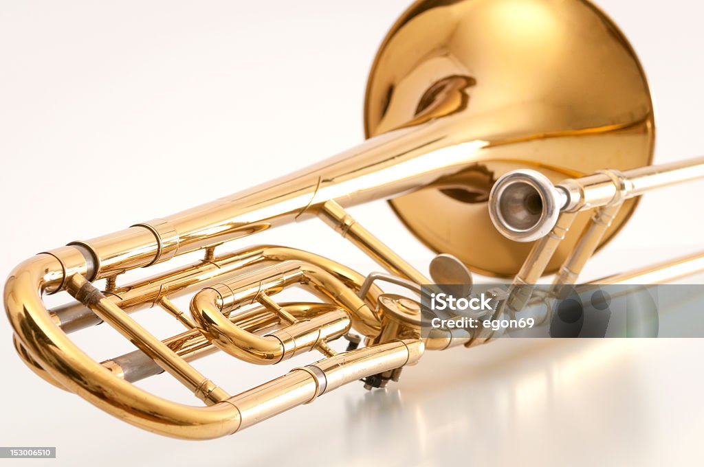 A closeup of the back of a golden trombone Old and used trombone on white background. Trombone Stock Photo