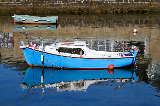 Fishing boats and masts reflected in the calm waters of a fishing harbor around sunset. Location: Dragør, Denmark.
