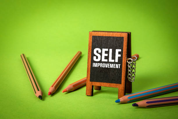 istock Self Improvement. Miniature chalk board and stationery on a green background 1530095561