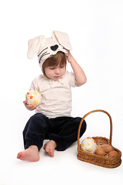 istock Easter bunny sitting next to basket holding toy chicken pensive 153009679