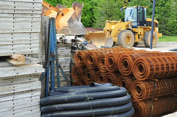 Various piles of building materials (concrete, tubing, wire) at a construction site. 