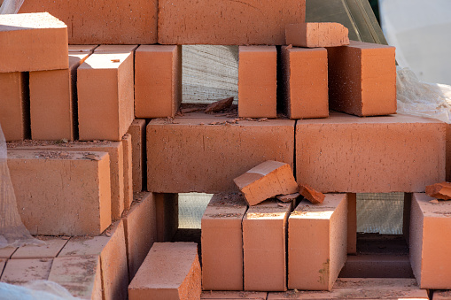 red bricks in a construction warehouse on the street. Building material red brick with holes. Solid clay bricks used for construction. Concept of repair and building materials.