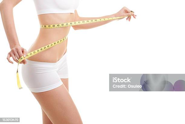 Athletic Woman Wrapping A Tape Measure Around Herself Stock Photo - Download Image Now