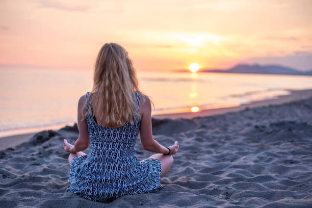 istock Woman meditating at the beach 1530140947