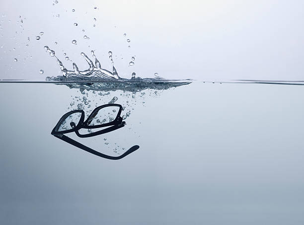 Pair of glasses falling in water stock photo