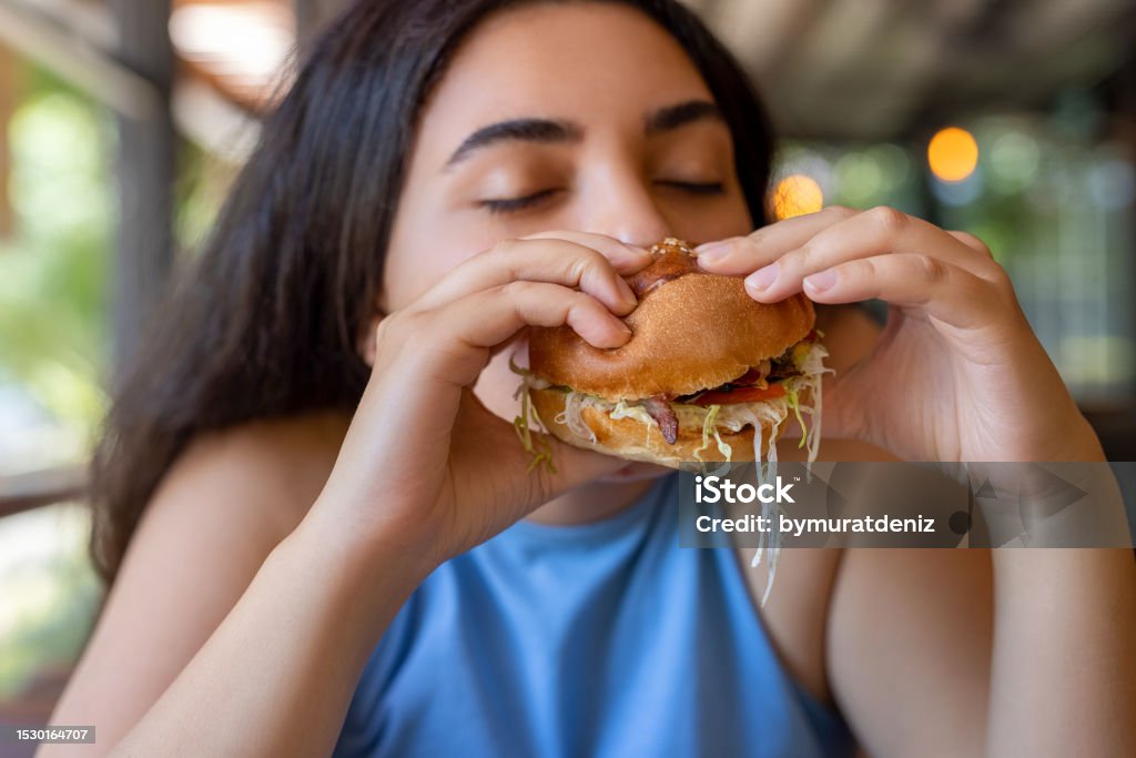 Woman eating hamburger 20-24 Years Stock Photo