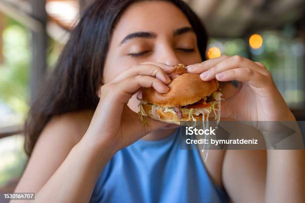 Woman Eating Hamburger Stock Photo - Download Image Now - 20-24 Years, Adult, Adults Only