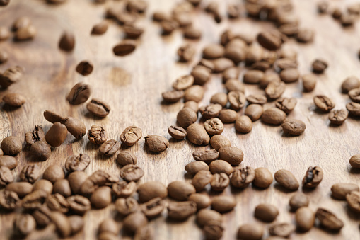 roasted coffee beans falling on wood table, shallow focus